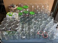 Full view of large assortment of glass canning jars of various sizes, along with lids and boxes of canning accessories.
