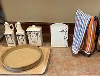 Close-up of stoneware pans, ceramic containers, ceramic cutting board, towel stand with kitchen towels