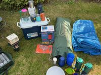 Cooler with assorted mugs and canopy bag at right