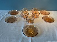 Full view of five opalescent peach Carnival Glass tea cups and five matching saucers arranged on a white surface.