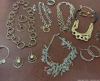 Overview of the lot showing mixed metal chain necklaces, earrings, and bracelet on brown surface.