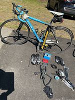 Blue and white CSK lightweight road bike with Shimano shoes and bike repair items laid out in front on asphalt.