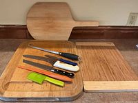 Three wooden cutting boards and six kitchen knives laid on a countertop.