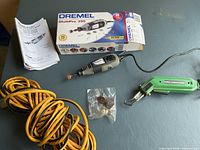 Dremel MultiPro 395 rotary tool with box, manual, and yellow extension cord alongside Engel soldering iron with accessory bits in small plastic bag.