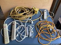 Full lot display of extension cords and power strips, showing items coiled on a blue surface.