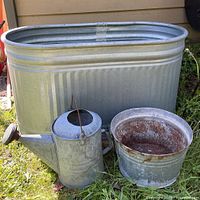 Front view showing oval stock tank, round tub, and watering can grouped outdoors