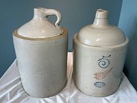 Photo of two large vintage stoneware jugs. One marked with Red Wing stamp and blue decorative number 5, the other unmarked.