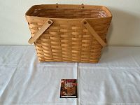 Front view of the rectangular Longaberger basket showing woven wood construction and attached wooden handles secured with copper fasteners.