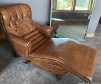 Front left three-quarter view showing brown chaise lounge upholstery, curved seat and tufted back.