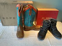 Both pairs of boots side by side with their respective boxes visible behind them on a white surface.