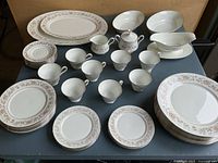Full set laid out showing plates of various sizes, cups, saucers, and serving pieces on dark table