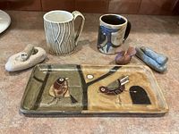 Whole lot showing 2 mugs, pottery tray, and shaped stones
