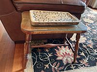 Side table angled view showing spindle legs, glass top, and woven wood surface, with carved wooden tray on top