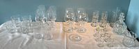Full set of glassware on a white tablecloth showing all pieces including stemware, water glasses, decanter, pitcher, and bowl