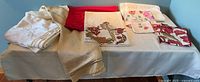 Overview photo of seven tablecloths, table runners, and napkins in multiple colors and fabric designs laid on table.