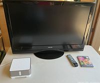 Front view of Toshiba 37-inch flat TV with remote and unopened Fight Club DVD on table, Sonos Connect amp on the left.