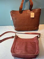 Two Frye leather bags: one new large woven leather tote with Frye & Co. paper tag, one vintage smaller leather crossbody bag