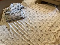 Photo showing both off-white bedspreads, one crocheted and one chenille, folded and laid out to show pattern and texture.