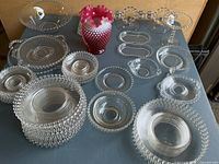 Lot contents on table showing multiple bubble glass bowls, plates, saucers, and decorative items including a red fuchsia vase