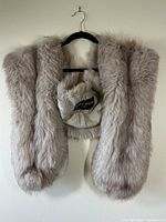 Taupe colored fur stole hanging on a hanger showing length and texture
