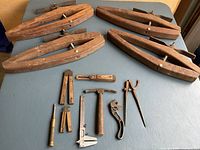 Full view of four large wooden clamps and assorted vintage precision tools including screwdrivers, hammer, wrench, compass and calipers.