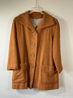Front view of turmeric colored wool jacket with button front and flap pockets