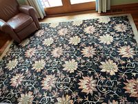 Full view of wool rug in living room under natural light, shows overall floral pattern and pile condition