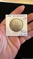 Photo showing the obverse side of the 1918 Newfoundland 50 cent silver coin in a protective holder with handwritten details about silver content and weight.