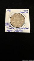 Front side of 1941 Canadian half dollar coin showing the Canadian Coat of Arms, encased in a cardboard holder with handwritten notes.