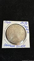 Front side of 1966 Canadian silver dollar coin in holder showing reverse design with canoe and inscriptions including 'CANADA DOLLAR' and year 1966.