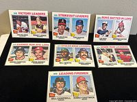 Nine 1976 O-Pee-Chee baseball cards featuring league statistical leaders in various categories, arranged on flat surface.