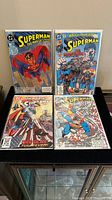 Four DC Superman comics laid out flat on a table, showing front covers with colorful graphics and characters.