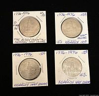 Four silver-colored Kennedy Half Dollar coins dated 1776-1976 in individual white cardboard holders with hand-written labels describing them as Bicentennial commemorative coins.