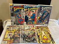 Six Superman comic books displayed on white surface showing front covers.