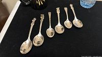 Set of 6 vintage collector spoons lined up showing decorative character handles