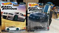 Two Hot Wheels Fast & Furious Premium cars in original packaging: white BMW M3 E46 with teal rims and black Lamborghini Aventador Coupe.
