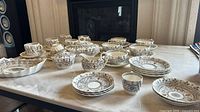 Wide view of entire Florence Copeland Spode china set including teacups, plates, serving dishes, and covered pieces displayed on table.