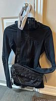 Black vintage Lululemon scuba hoodie with front zipper and belt bag displayed on hanger