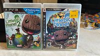 Photo of two PlayStation 3 game cases side by side for Little Big Planet and Little Big Planet 2 games.