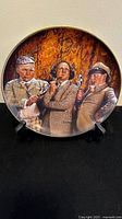 Front view of the round collectors plate showing the three stooges in Sherlock Holmes attire with pipes and magnifying glass.