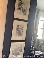 Three stacked framed pen and ink prints by Simone Hudon hung on wall.