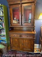 Front view of antique walnut sideboard upper cabinet with glass doors and wooden framed panels.