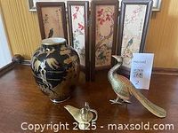 Image showing four items: black and gold Chinoiserie vase, three-panel tabletop screen with floral and bird designs, brass peacock figurine, and brass Aladdin's lamp.