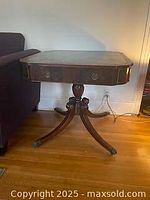 Full view of square wooden games table with leather top and drawer against a white wall near sofa