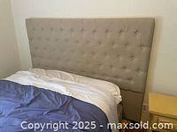 Full view of fabric covered queen size bed headboard attached to bed base, beige upholstery with button tufting.