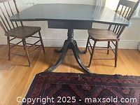 Full view of the painted Duncan Phyfe style drop leaf table with two wooden chairs, showing the overall form and finish.