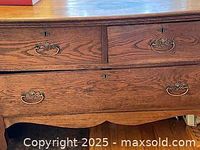 Close-up view of drawer handles and wood grain on oak chest.