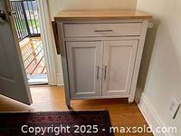 White rolling kitchen island cupboard, front view with closed doors and drop leaf folded down