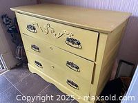 Front angle view of three drawer yellow rustic farmhouse style dresser on tile floor.