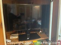 Front view of 32-inch Toshiba Fire TV mounted on its stand with visible remote and small white device beside it.